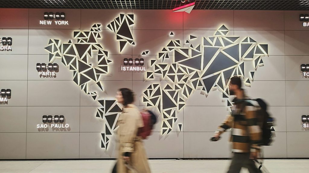 personnes qui circulent et une map monde en arrière plan sur le mur